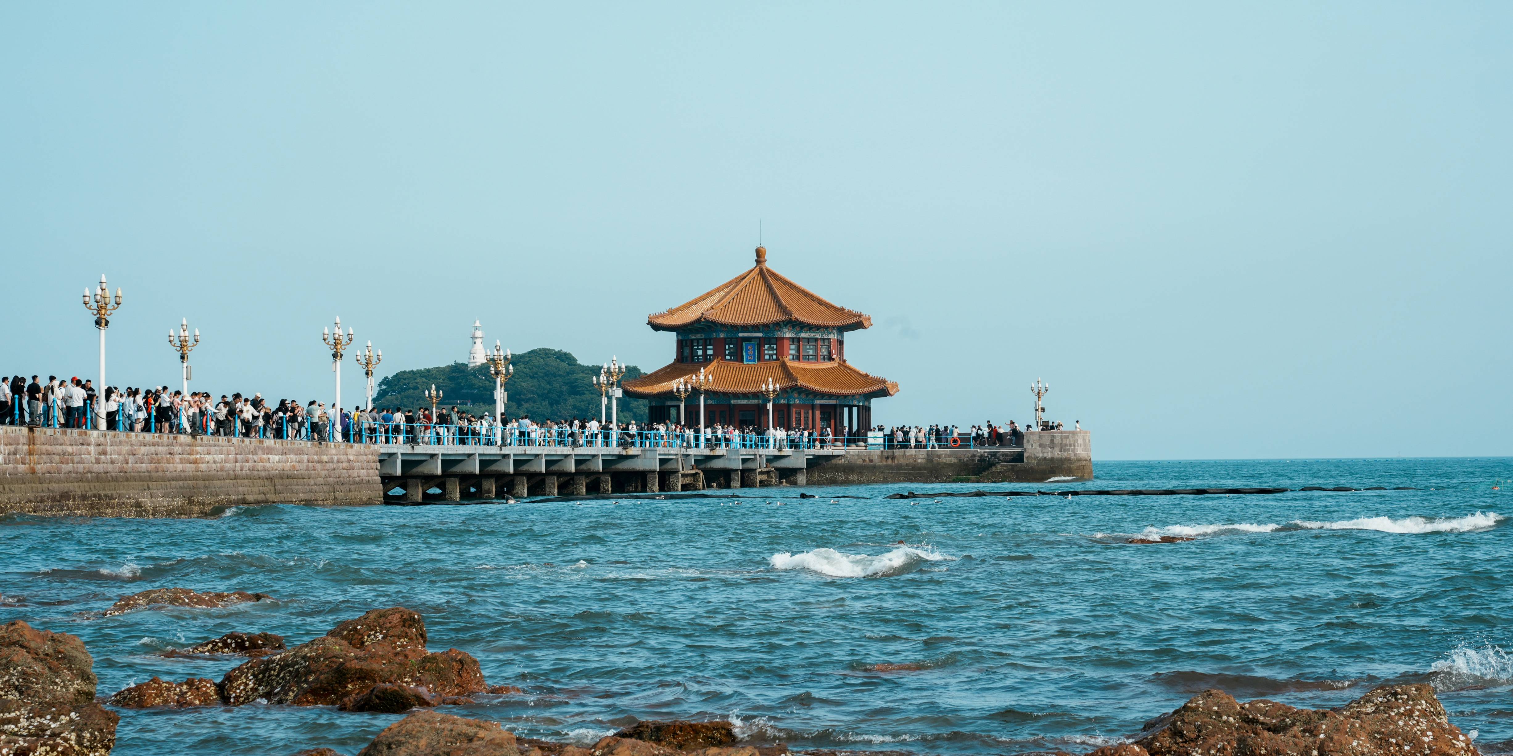 a group of people standing on a pier next to the ocean