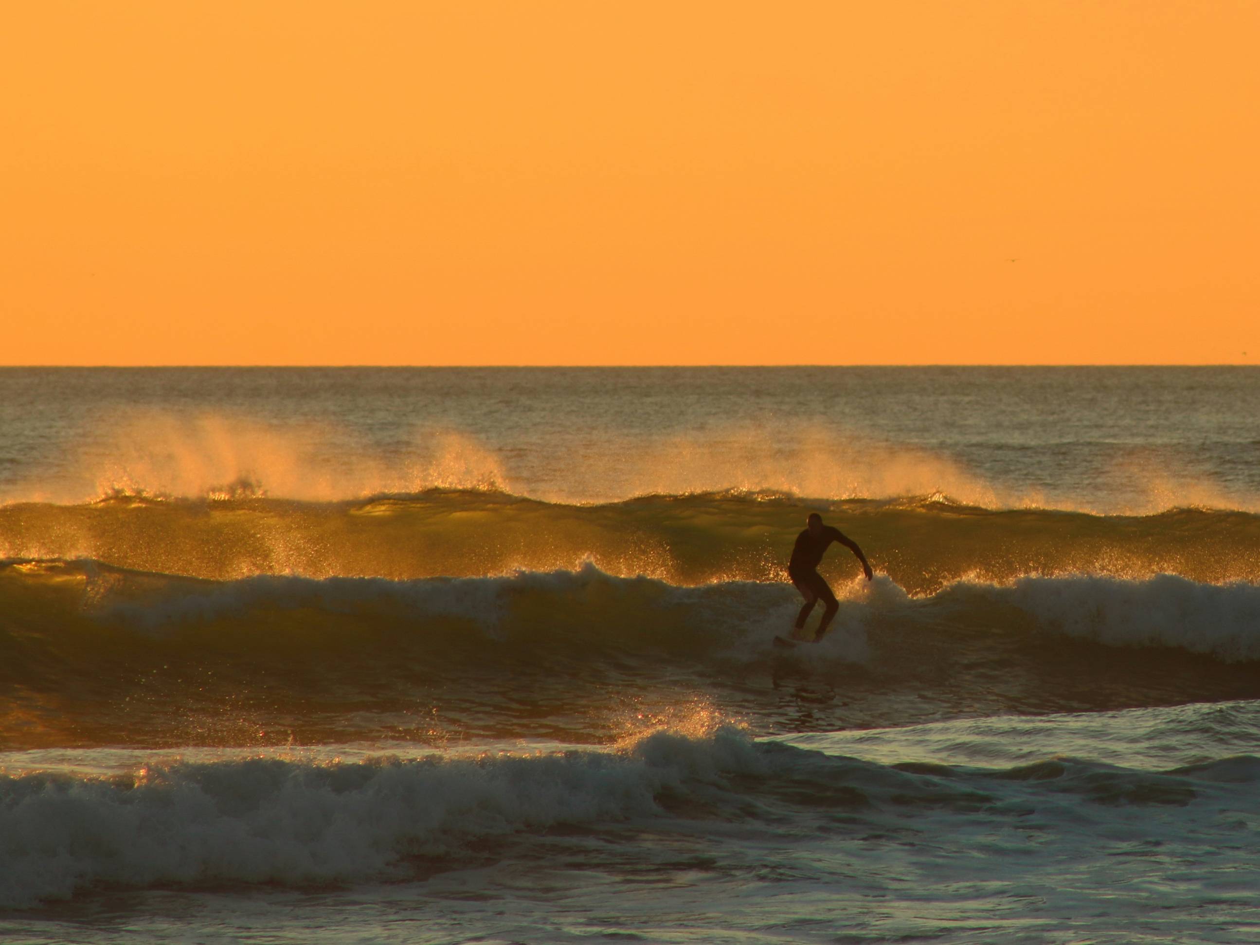 man surfing under yellow sky during daytime