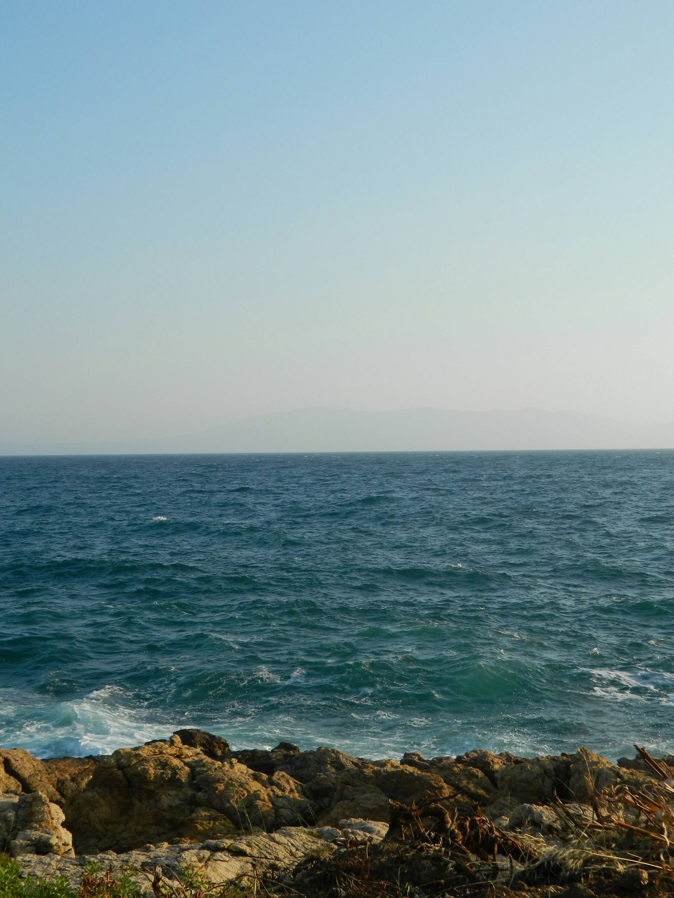 a rocky beach with a body of water in the background