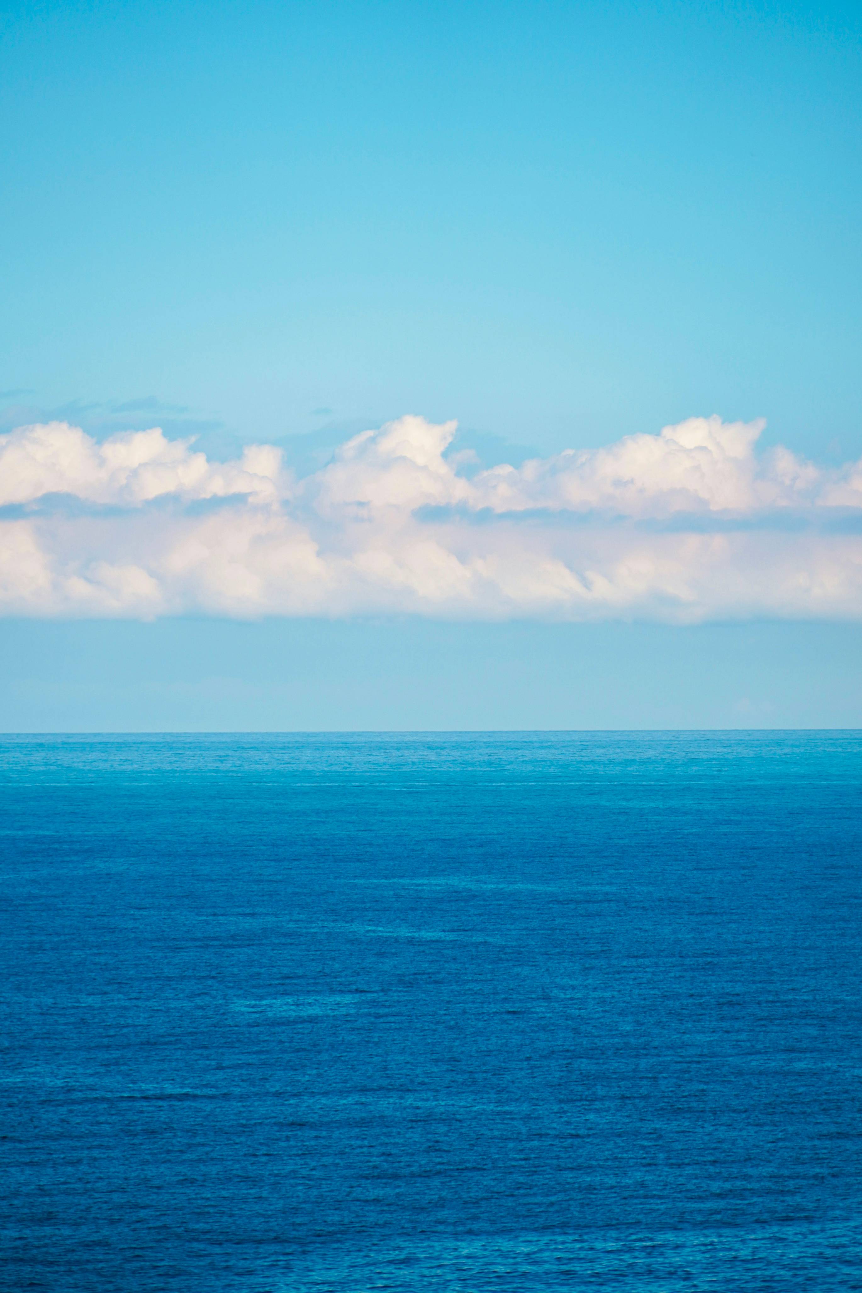 a large body of water sitting under a cloudy blue sky
